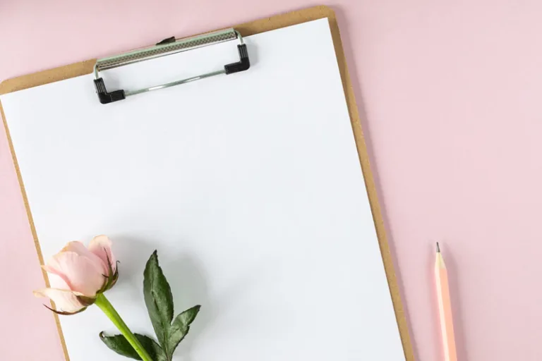 Klemmbrett mit Rose und Bleistift auf rosa Hintergrund